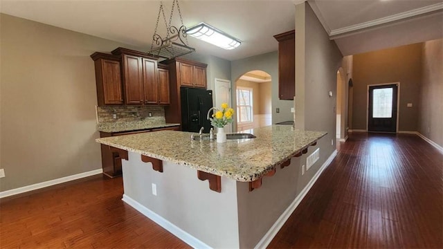 kitchen featuring sink, a breakfast bar area, dark hardwood / wood-style floors, light stone countertops, and black refrigerator with ice dispenser
