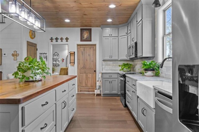 kitchen with dark wood-type flooring, wood ceiling, decorative backsplash, stainless steel appliances, and wood counters