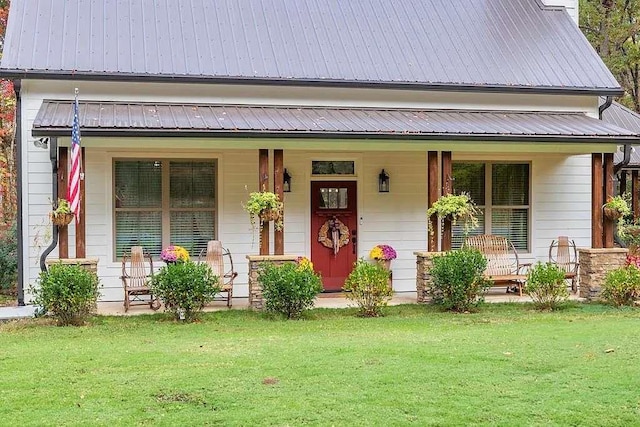 view of front facade with covered porch, metal roof, and a front yard