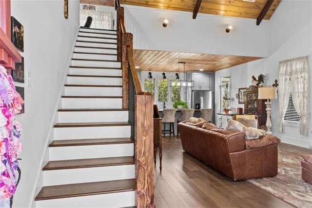 stairway with beamed ceiling, wood ceiling, and hardwood / wood-style flooring