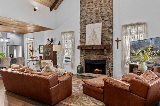 living room featuring beamed ceiling, high vaulted ceiling, wood finished floors, wooden ceiling, and a fireplace