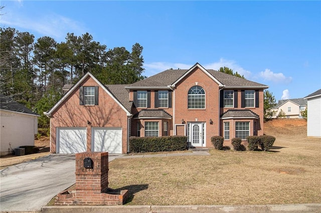 colonial house with driveway, a garage, a front lawn, and brick siding