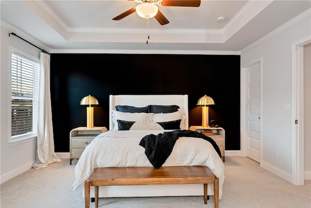 carpeted bedroom with a tray ceiling, ornamental molding, and ceiling fan