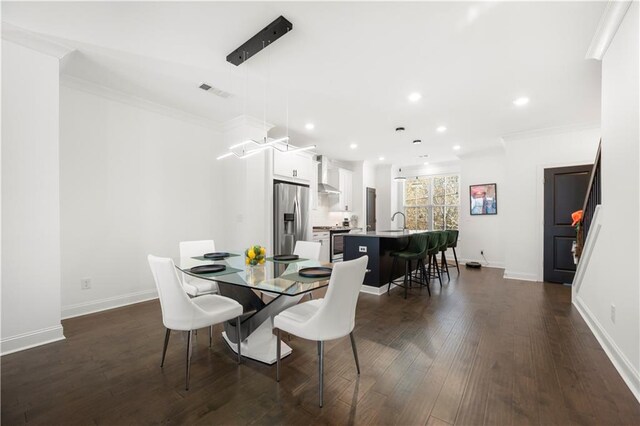 dining area with crown molding, dark wood-type flooring, and sink