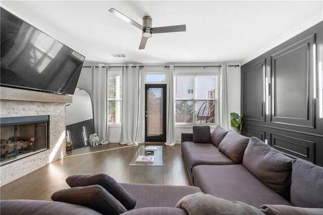 living room with a fireplace, ceiling fan, dark hardwood / wood-style flooring, and ornamental molding