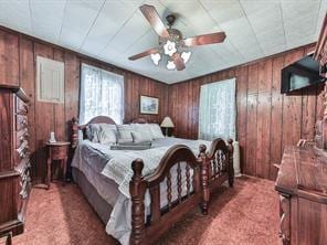 carpeted bedroom with ceiling fan and wooden walls