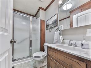 bathroom with vanity, a shower with shower door, ornamental molding, and toilet