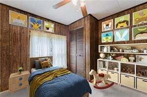 bedroom featuring a closet, wood walls, and ceiling fan