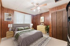 carpeted bedroom featuring a closet, wood walls, and ceiling fan