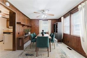 dining area with wood walls and ceiling fan