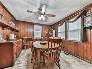 dining room featuring ceiling fan and wood walls