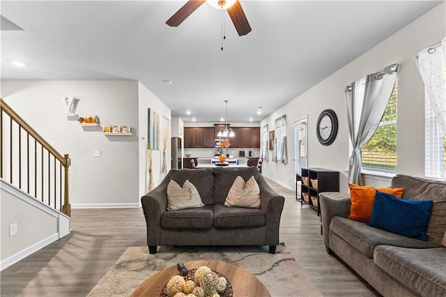 living room featuring wood-type flooring and ceiling fan with notable chandelier