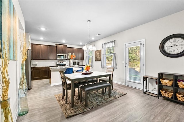 dining space featuring light hardwood / wood-style floors and a notable chandelier