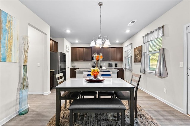 dining room with light wood-type flooring and an inviting chandelier