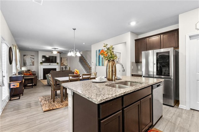 kitchen featuring a center island with sink, sink, light wood-type flooring, dark brown cabinets, and stainless steel appliances