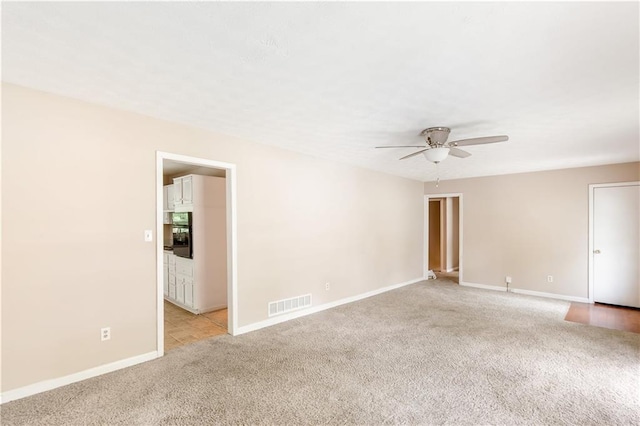 empty room featuring baseboards, a ceiling fan, light colored carpet, and visible vents