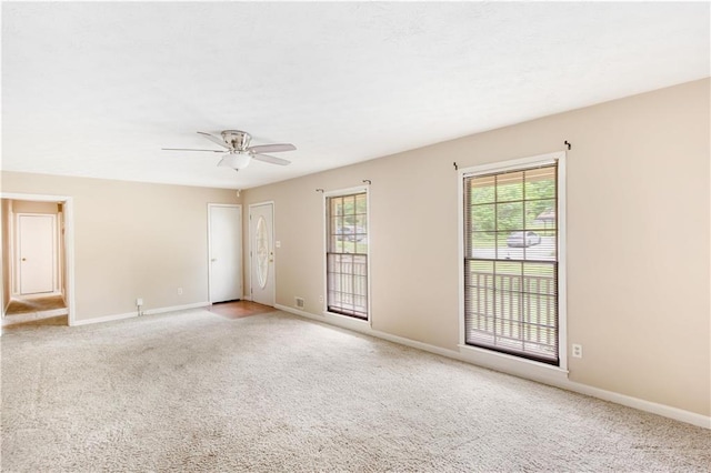 empty room featuring light colored carpet, a ceiling fan, and baseboards