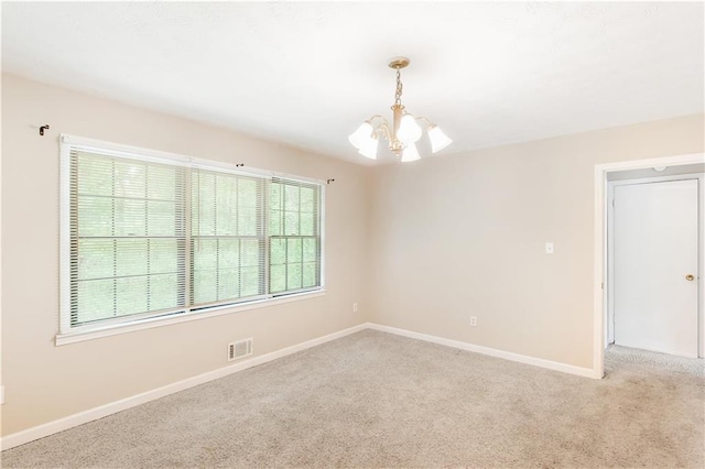 empty room with baseboards, an inviting chandelier, and light carpet