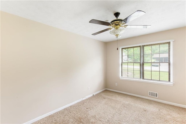 empty room with a ceiling fan, baseboards, visible vents, and light carpet