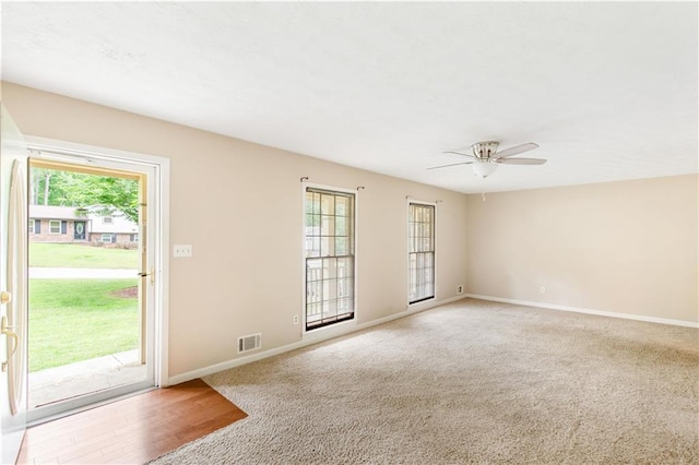 empty room featuring ceiling fan, visible vents, light carpet, and baseboards
