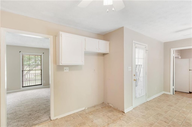 kitchen featuring baseboards, freestanding refrigerator, ceiling fan, and white cabinets