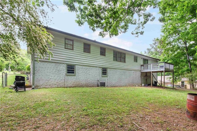 rear view of property featuring fence, a yard, and a wooden deck
