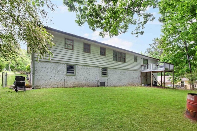 rear view of house with a lawn, a deck, and fence