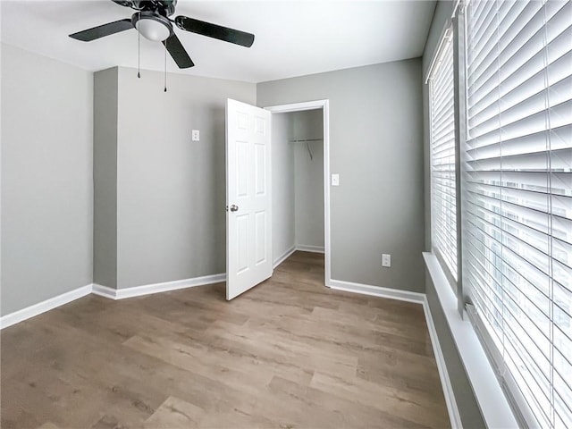 unfurnished bedroom featuring ceiling fan, light wood-style floors, a closet, and baseboards