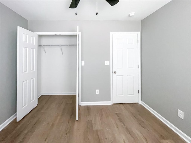 unfurnished bedroom featuring a closet, wood finished floors, a ceiling fan, and baseboards