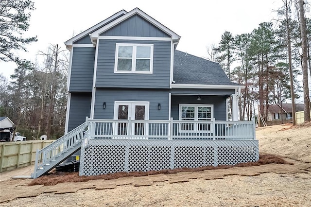 back of house with board and batten siding, fence, a wooden deck, and a shingled roof