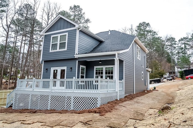 rear view of house featuring roof with shingles, board and batten siding, and a wooden deck