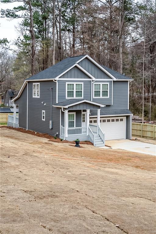 view of front of home with covered porch, driveway, board and batten siding, and an attached garage