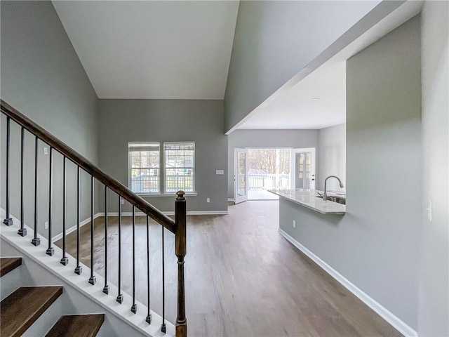 staircase with a high ceiling, baseboards, and wood finished floors