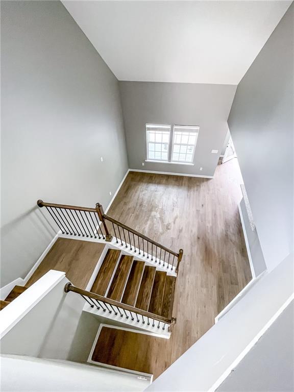 staircase featuring vaulted ceiling, wood finished floors, and baseboards