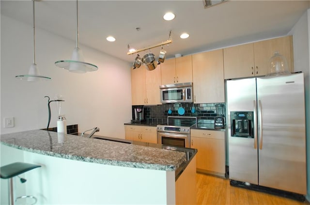 kitchen with appliances with stainless steel finishes, a sink, light brown cabinetry, backsplash, and recessed lighting