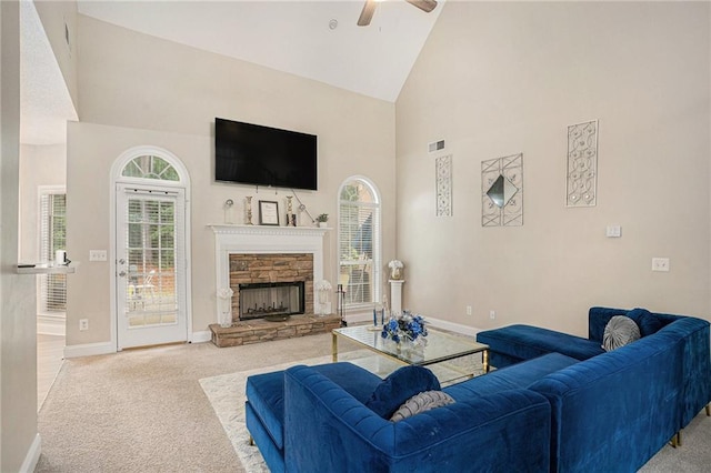 carpeted living area featuring ceiling fan, visible vents, baseboards, a fireplace, and high vaulted ceiling