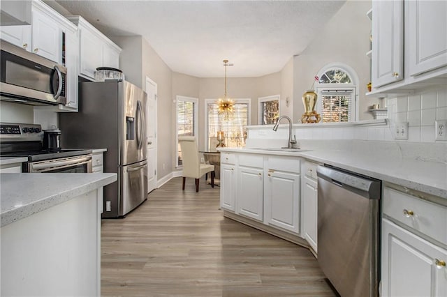 113 Glenmore Ln, Mcdonough, GA 30253 - kitchen featuring appliances with stainless steel finishes, a sink, white cabinets, light wood-style floors, and a peninsula