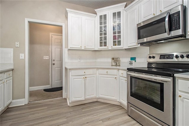 113 Glenmore Ln, Mcdonough, GA 30253 - kitchen with stainless steel appliances, light wood finished floors, white cabinetry, and decorative backsplash