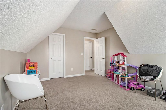 playroom with lofted ceiling, a textured ceiling, visible vents, and carpet flooring
