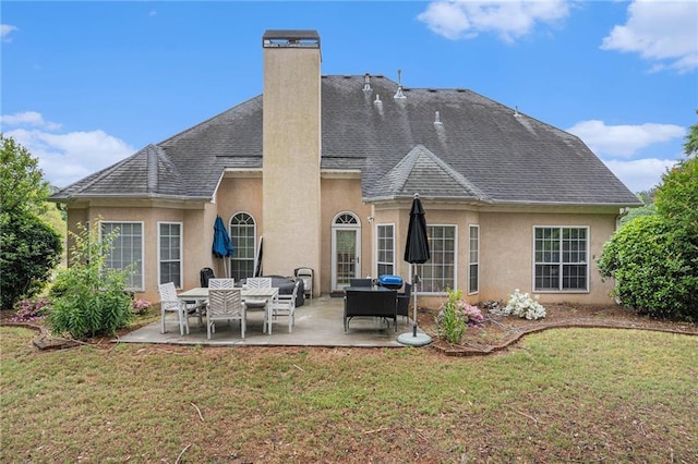 back of house featuring a chimney, a patio, stucco siding, and a lawn