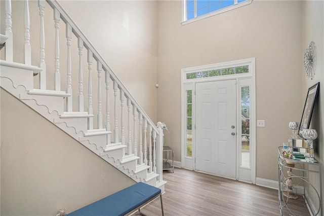 entryway featuring stairway, wood finished floors, baseboards, and a high ceiling