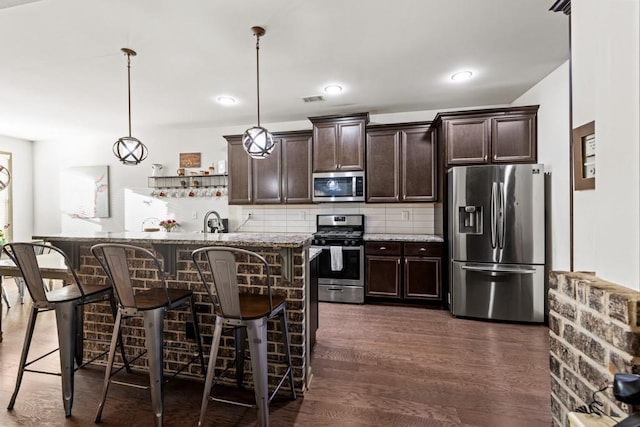 kitchen featuring stainless steel appliances, a kitchen breakfast bar, dark hardwood / wood-style floors, decorative light fixtures, and dark brown cabinets