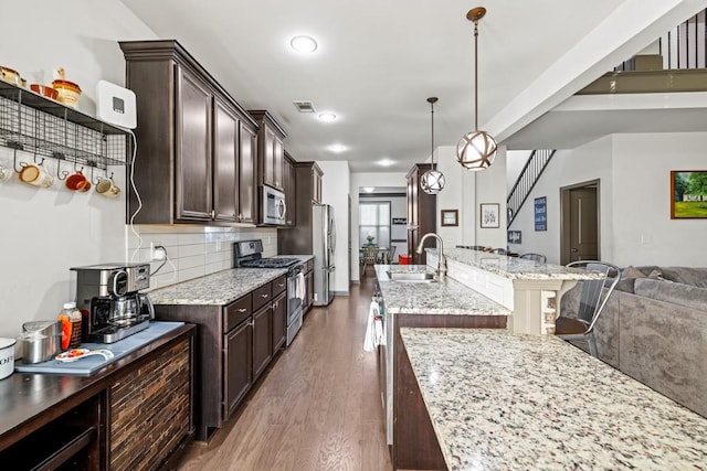 kitchen featuring hanging light fixtures, sink, dark hardwood / wood-style floors, appliances with stainless steel finishes, and light stone counters