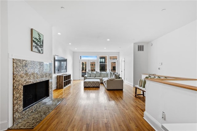 living room featuring french doors, a fireplace, and light hardwood / wood-style flooring