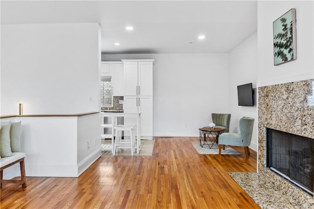 sitting room with a high end fireplace and light wood-type flooring