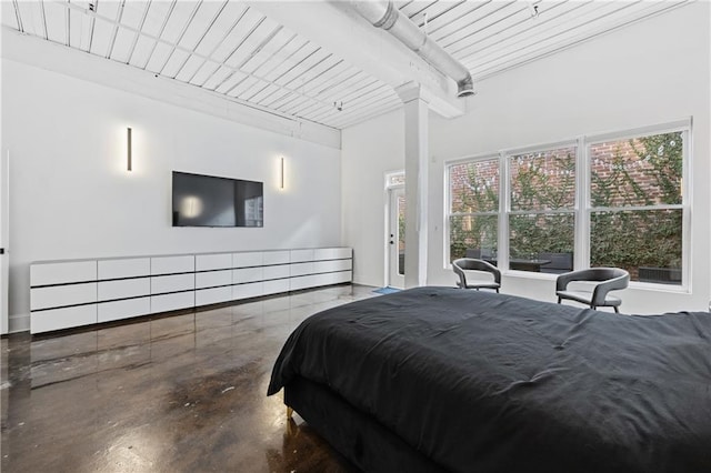 bedroom with concrete flooring, decorative columns, and beam ceiling