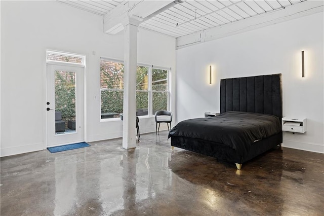 bedroom featuring multiple windows, access to exterior, concrete floors, and beamed ceiling