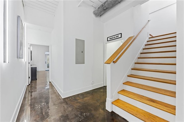 stairway featuring electric panel and a high ceiling