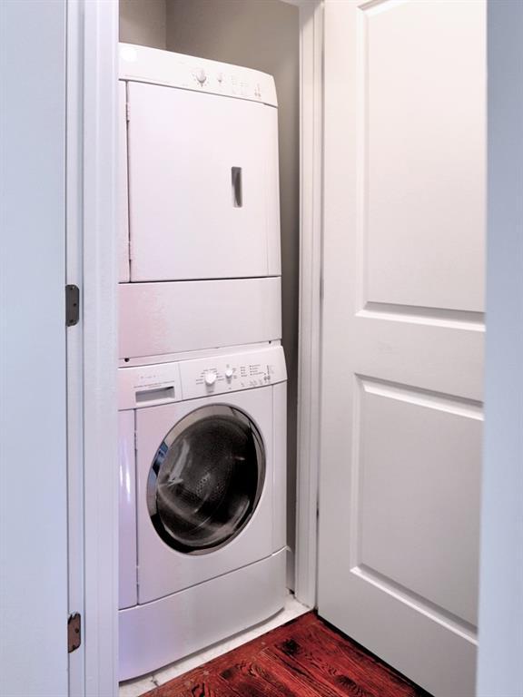 washroom with dark hardwood / wood-style floors and stacked washer and clothes dryer