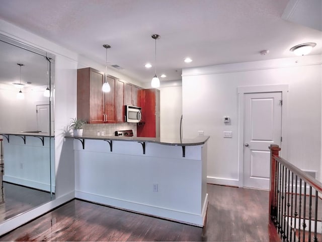 kitchen with kitchen peninsula, dark hardwood / wood-style flooring, and pendant lighting